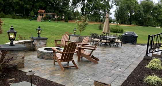 Downington outdoor living space provides separate areas for eating and relaxing around the fire pit.