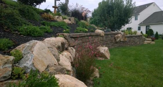 Retaining wall with boulders holds back sloping yard in Douglassville, PA