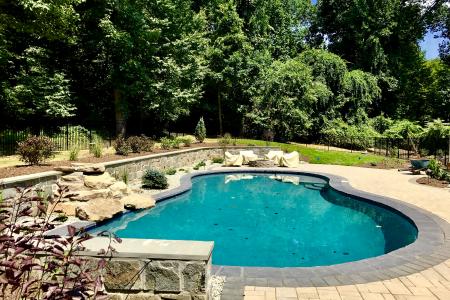 Stone veneer wall with patio pavers and pool in Glenmoore, PA