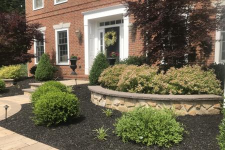 Curved stone wall and red brick colonial house in Malvern, PA