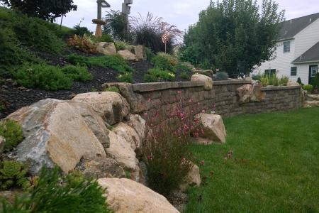 This retaining wall in Douglassville, Pa uses boulders and Techo-Bloc wall block to create visual interest while reinforcing a bank and controlling soil erosion.